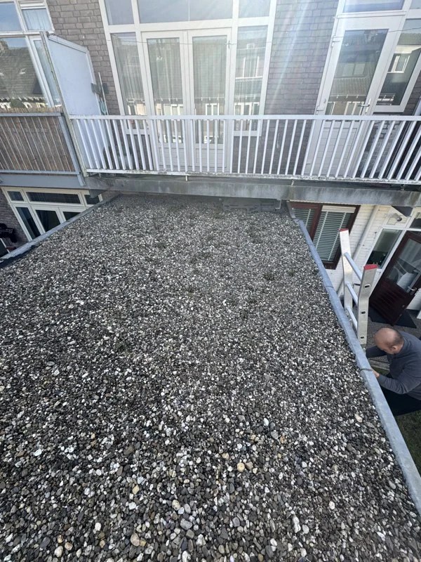 Gravel-covered flat roof before renewing the bitumen roofing in Haarlem-Noord